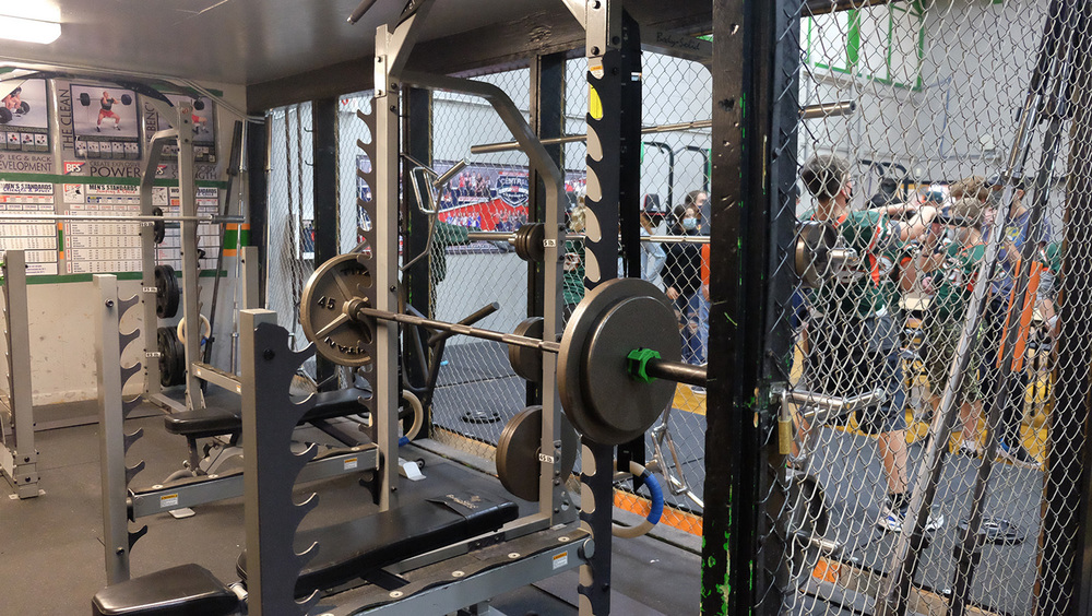 Weight room with view of student PE class through cage fence